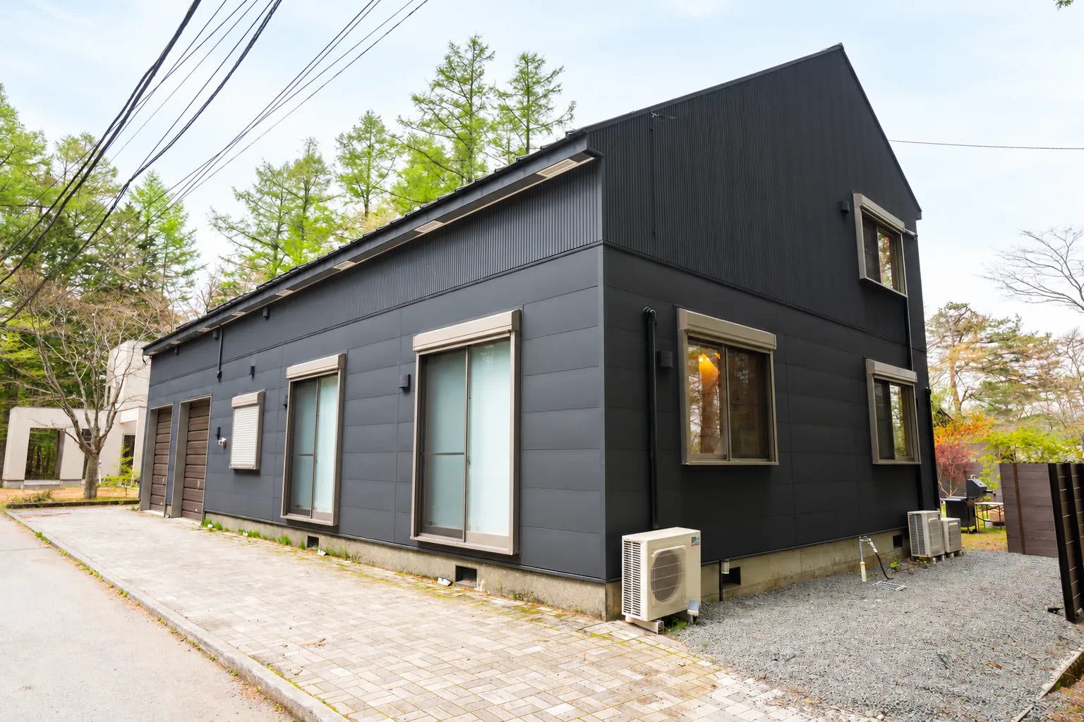 黒い外壁と庭へ続く通路がある建物側面